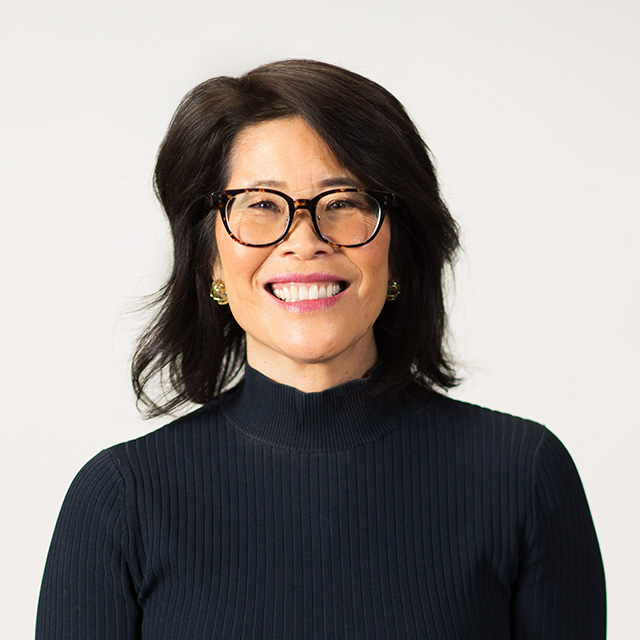 A woman wearing glasses and a turtle neck top.