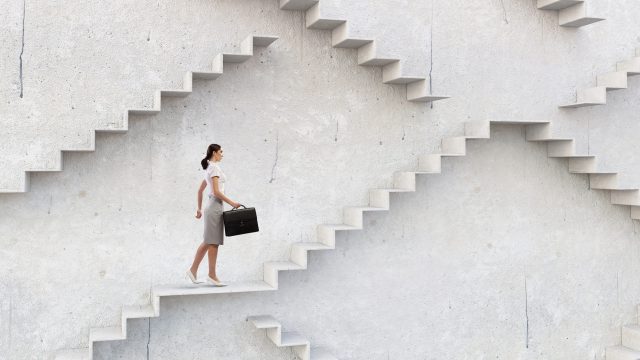 A businesswoman climbs a staircase as symbol of self-development and career growth.