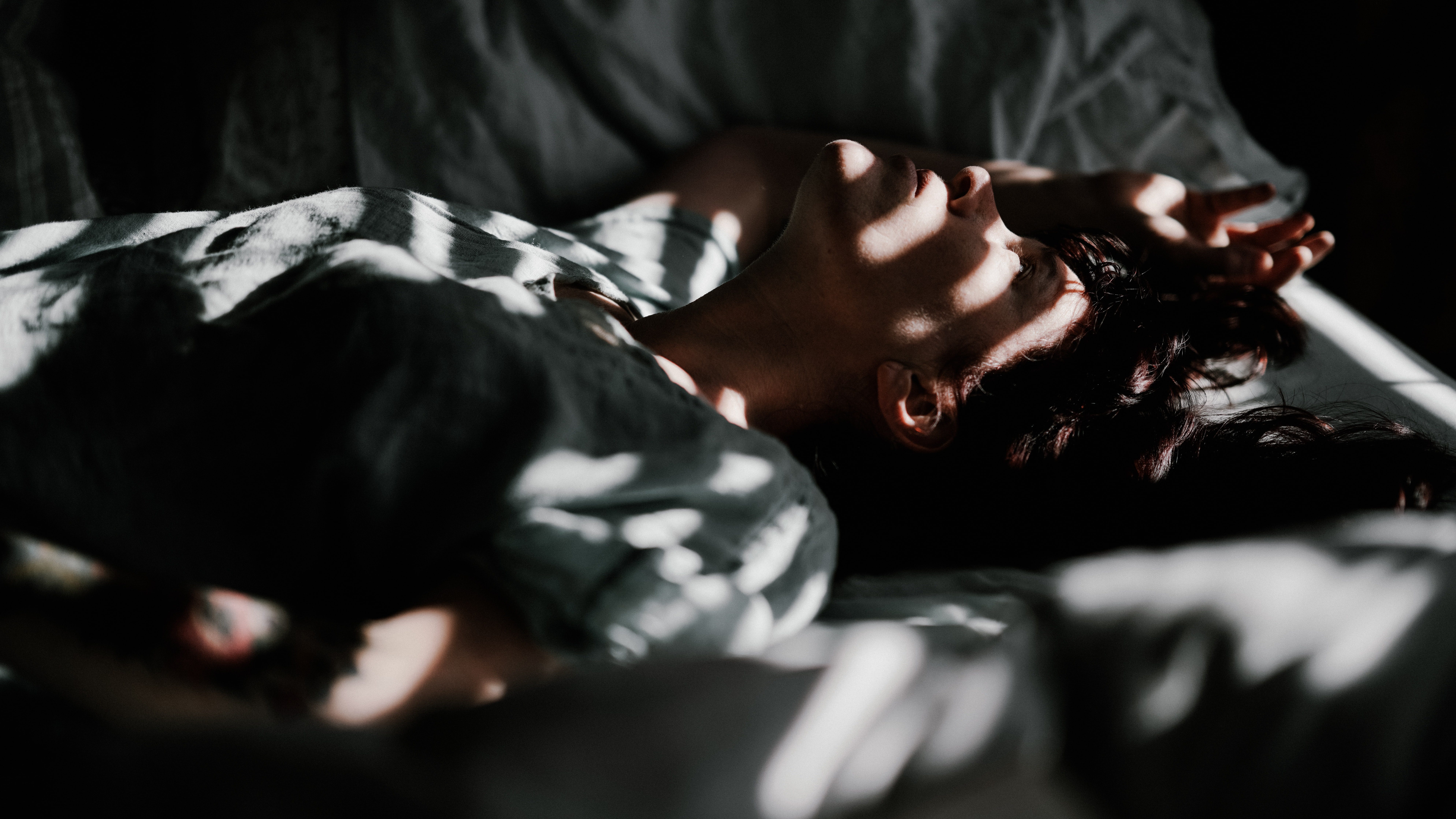 A person lying in bed lacking sleep due to daylight saving time.