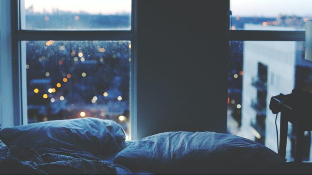 Pillows on a bed overlooking a city illustrating how sleep loss affects cognitive decline.