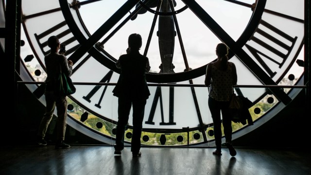 Three people standing on the inside of a clock illustrating an article on daylight saving time.