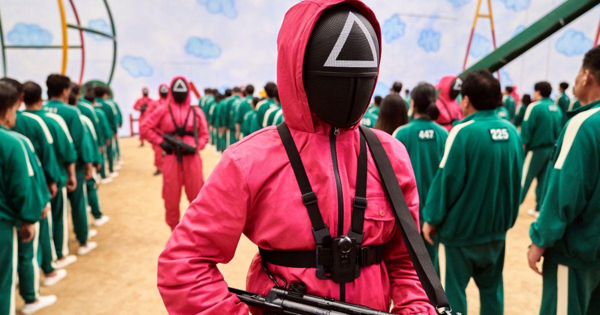 A still image from Squid Games showing guards with guns lining up contestants of the death game.
