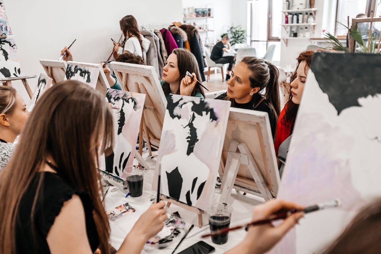 Young women paint with brushes in an art class.