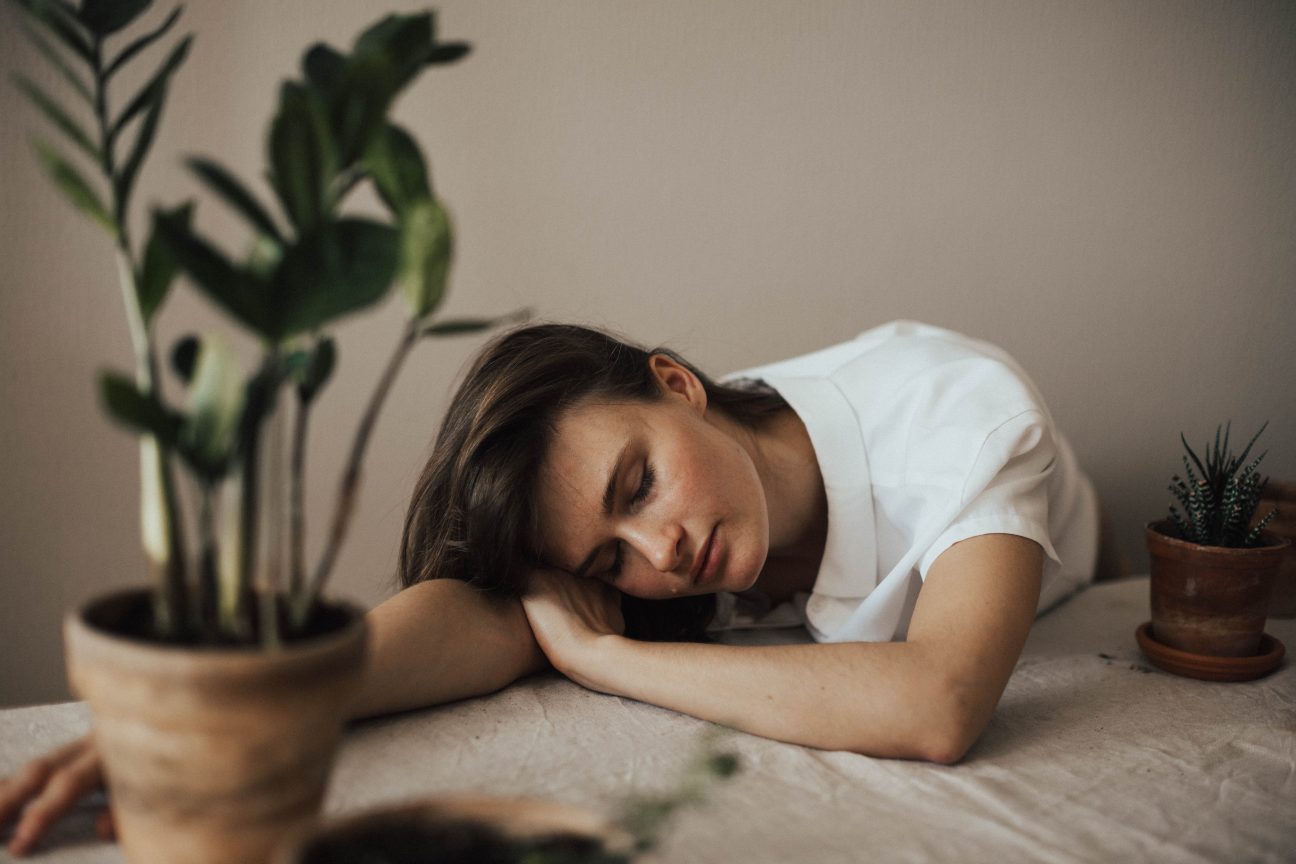 A woman rests next to her houseplants.