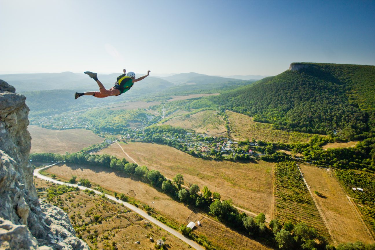Base-jumper takes a leap from a cliff top.