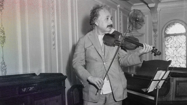 a man playing a violin in front of a piano.