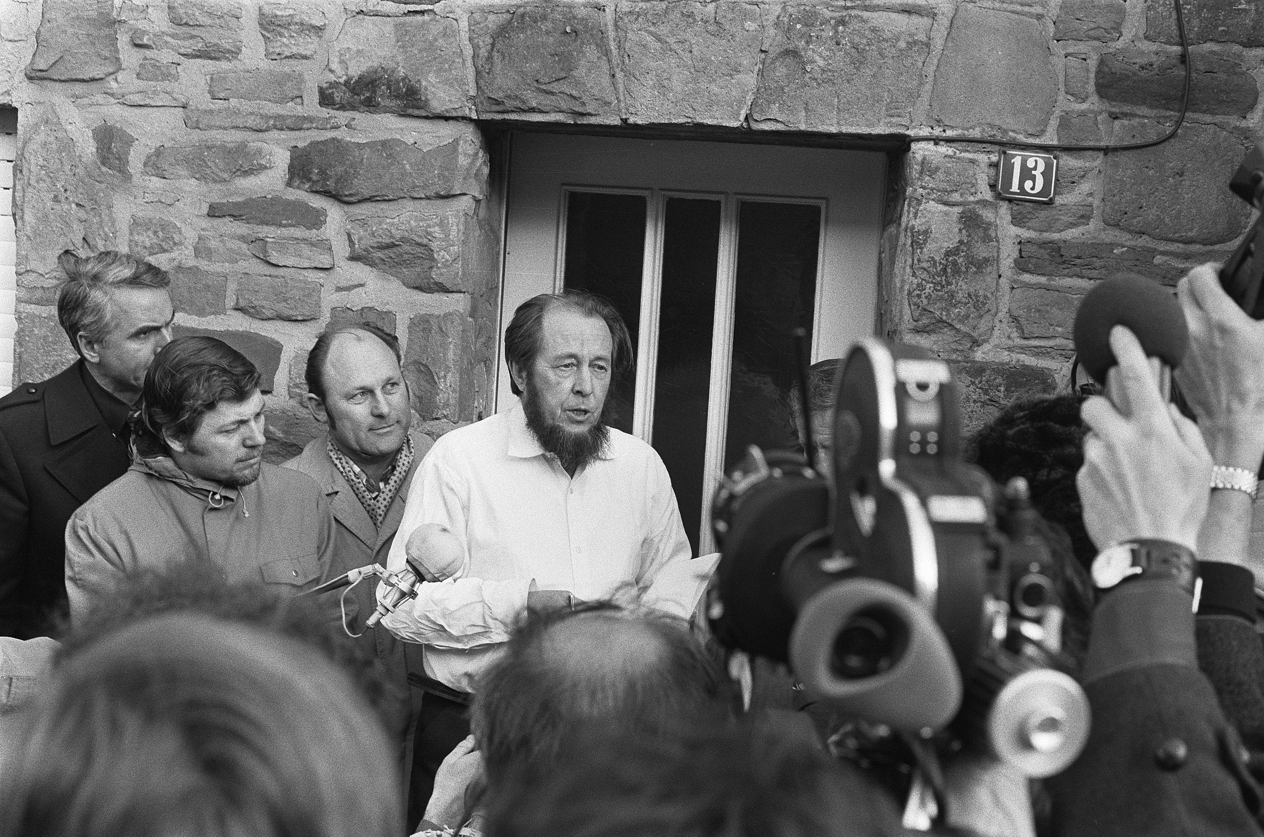 a black and white photo of a man surrounded by people.