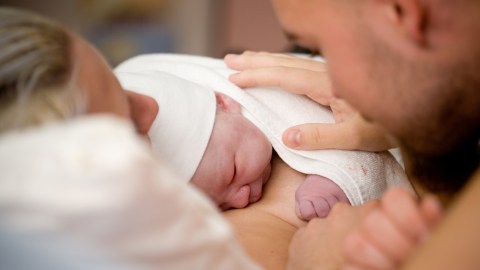 a man and woman holding a newborn baby