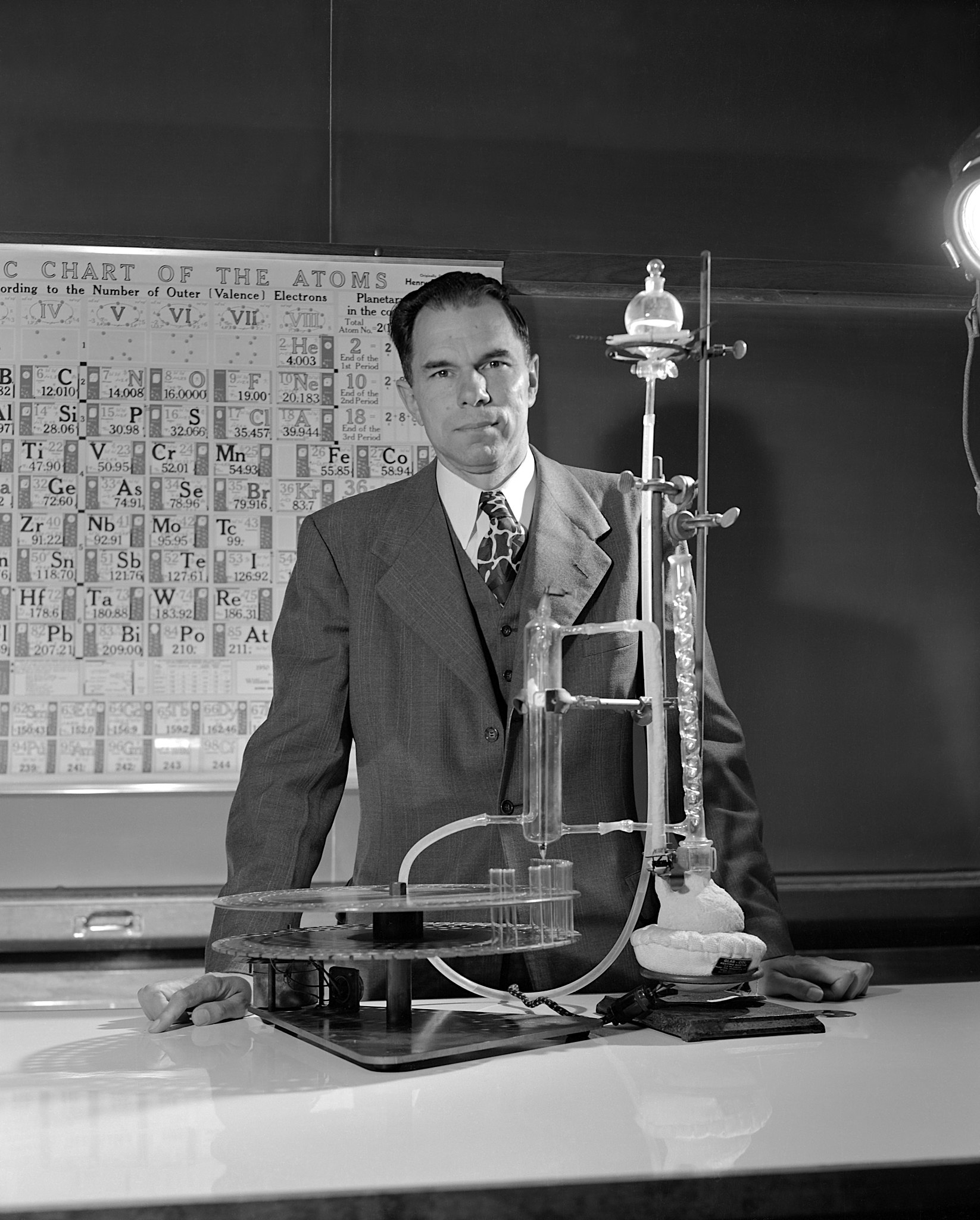 a man in a suit and tie standing in front of a machine.