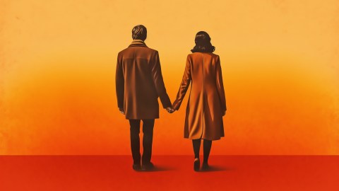 a man and a woman holding hands in front of an orange background.