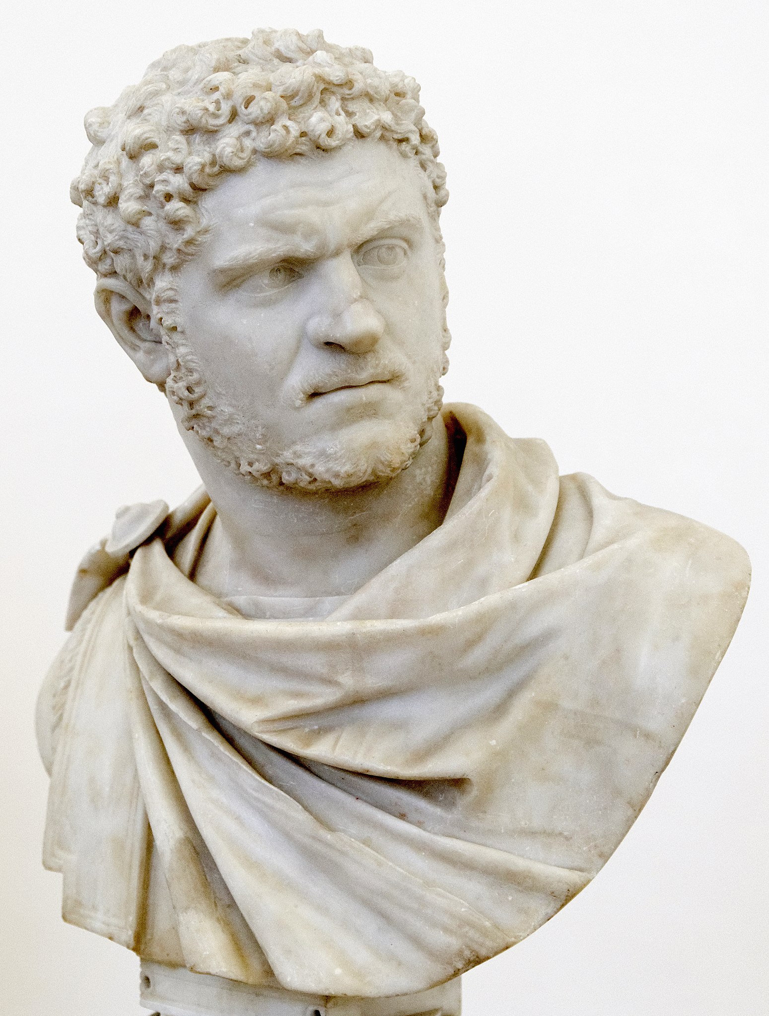 a white marble bust of a man wearing a scarf.