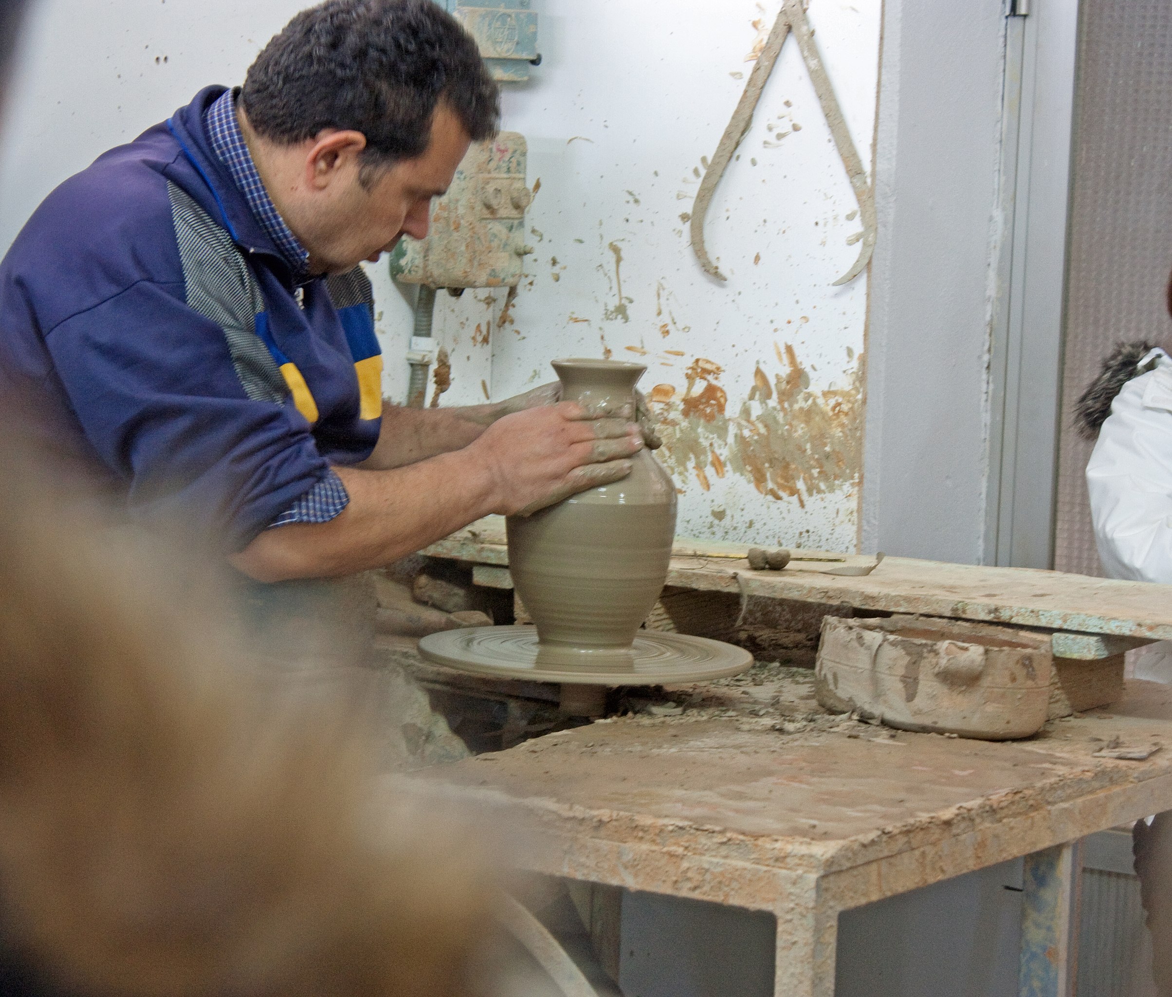 a man making a vase on a pottery wheel.