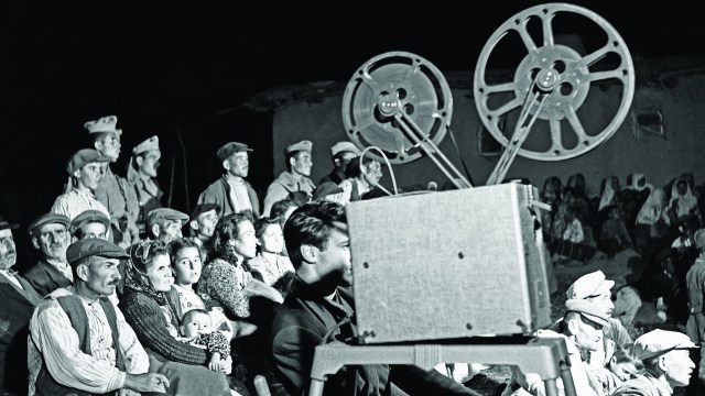 a black and white photo of a crowd of people watching a movie.