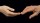 two hands reaching for each other on a black background.