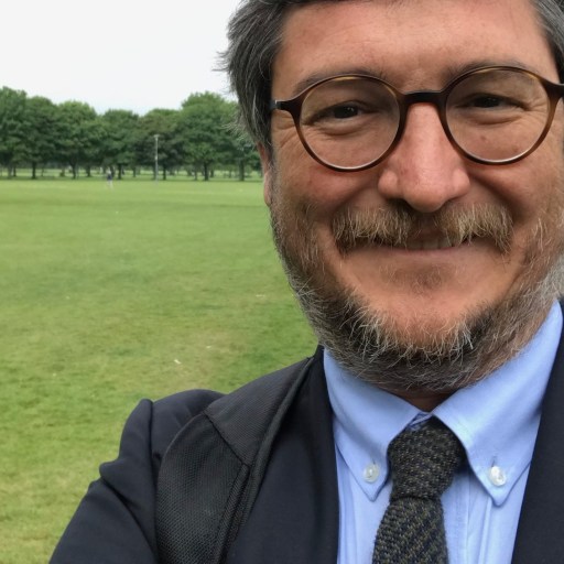 a man in a suit and tie is taking a selfie in a park.