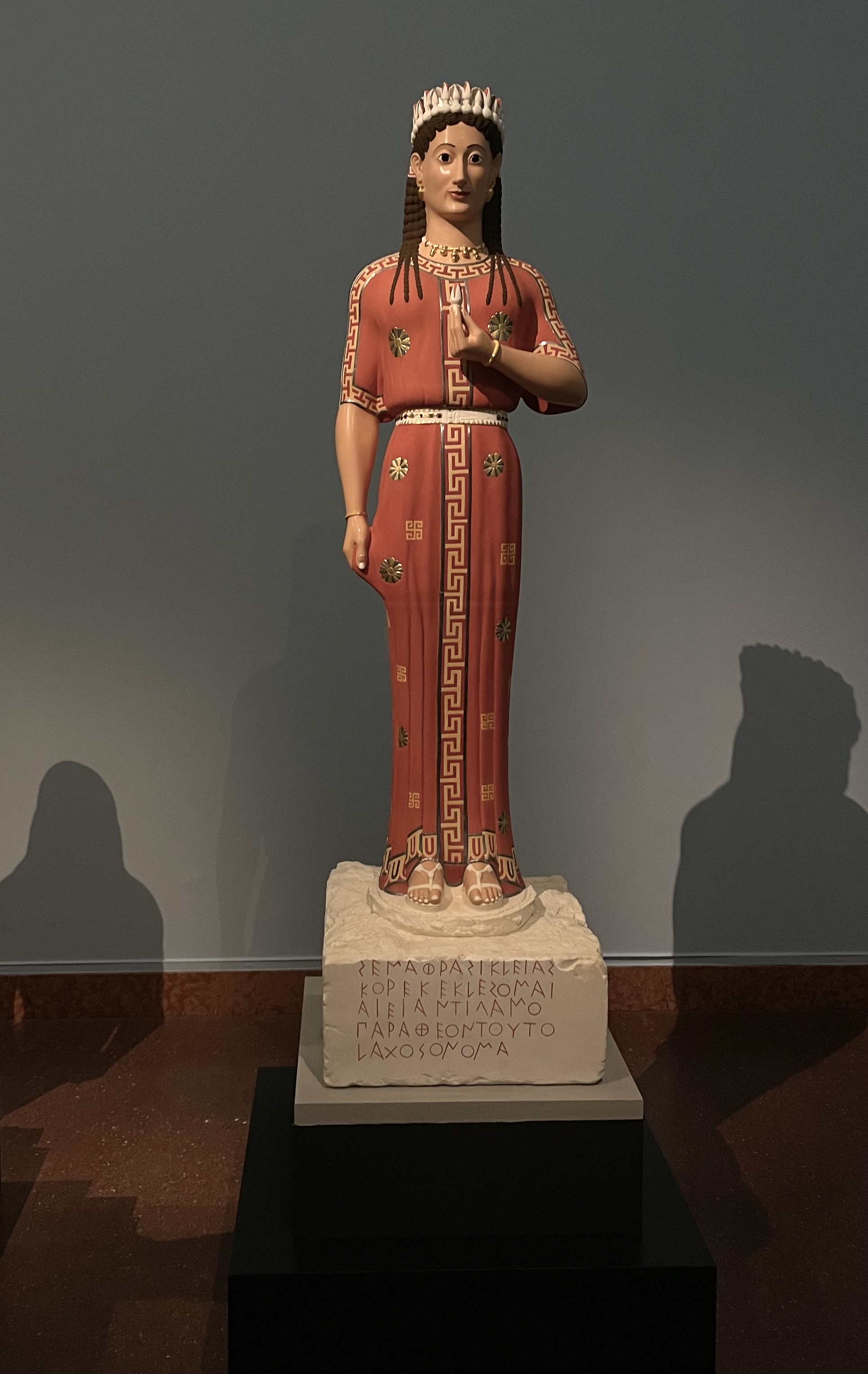 A Greek statue of a woman is on display in a museum.
