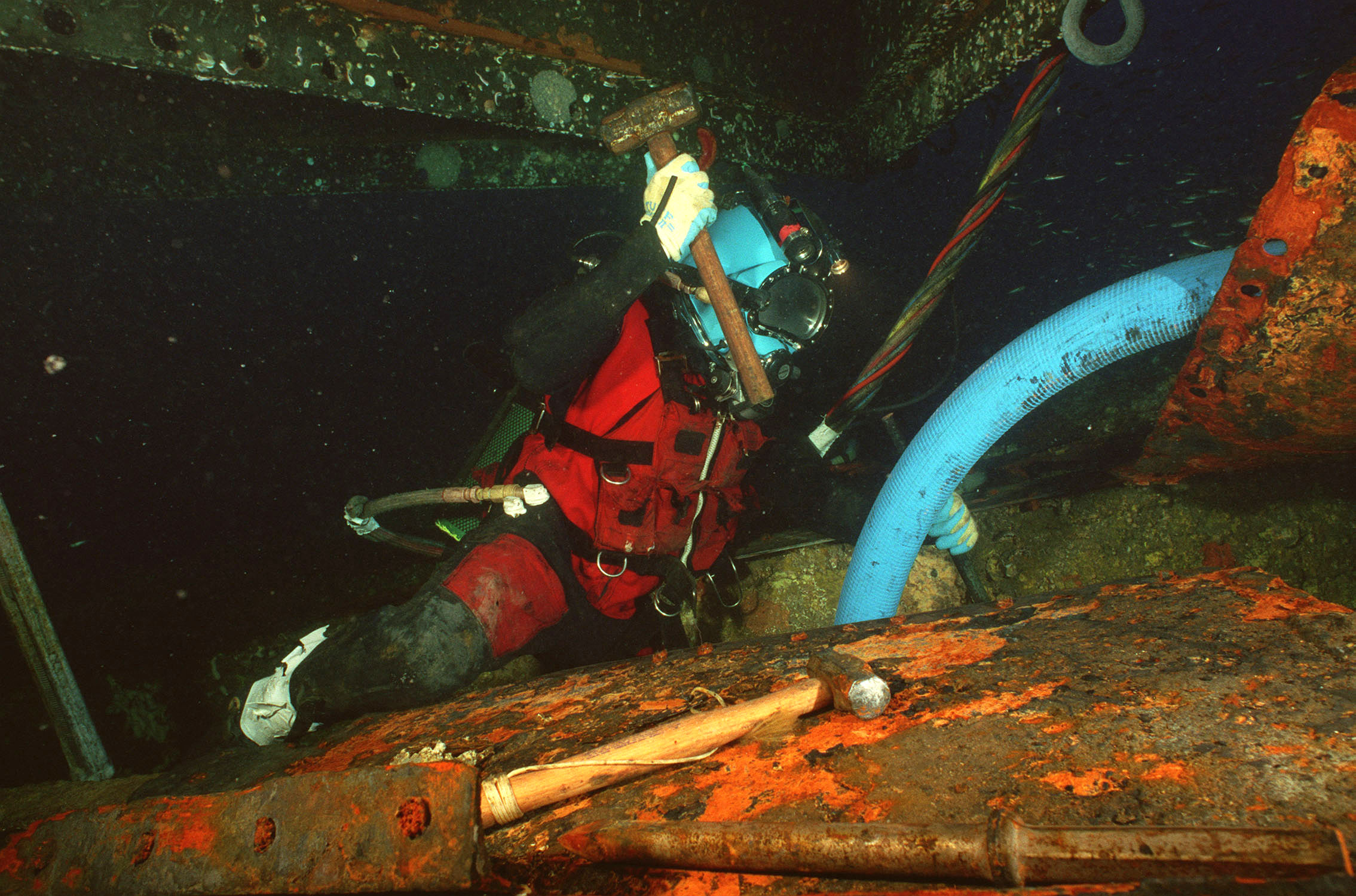 a scuba diver working on a rusty piece of equipment.