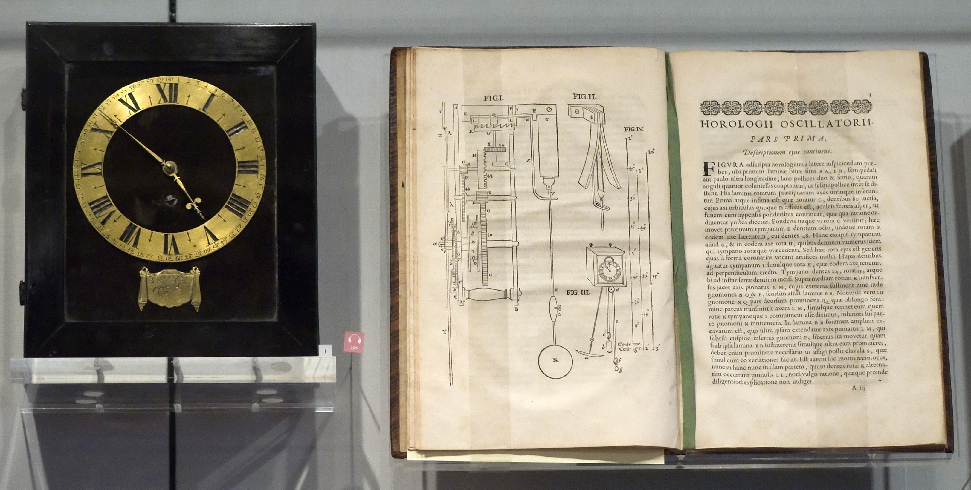 A clock, believed to be the first in America, showcased beside a book.