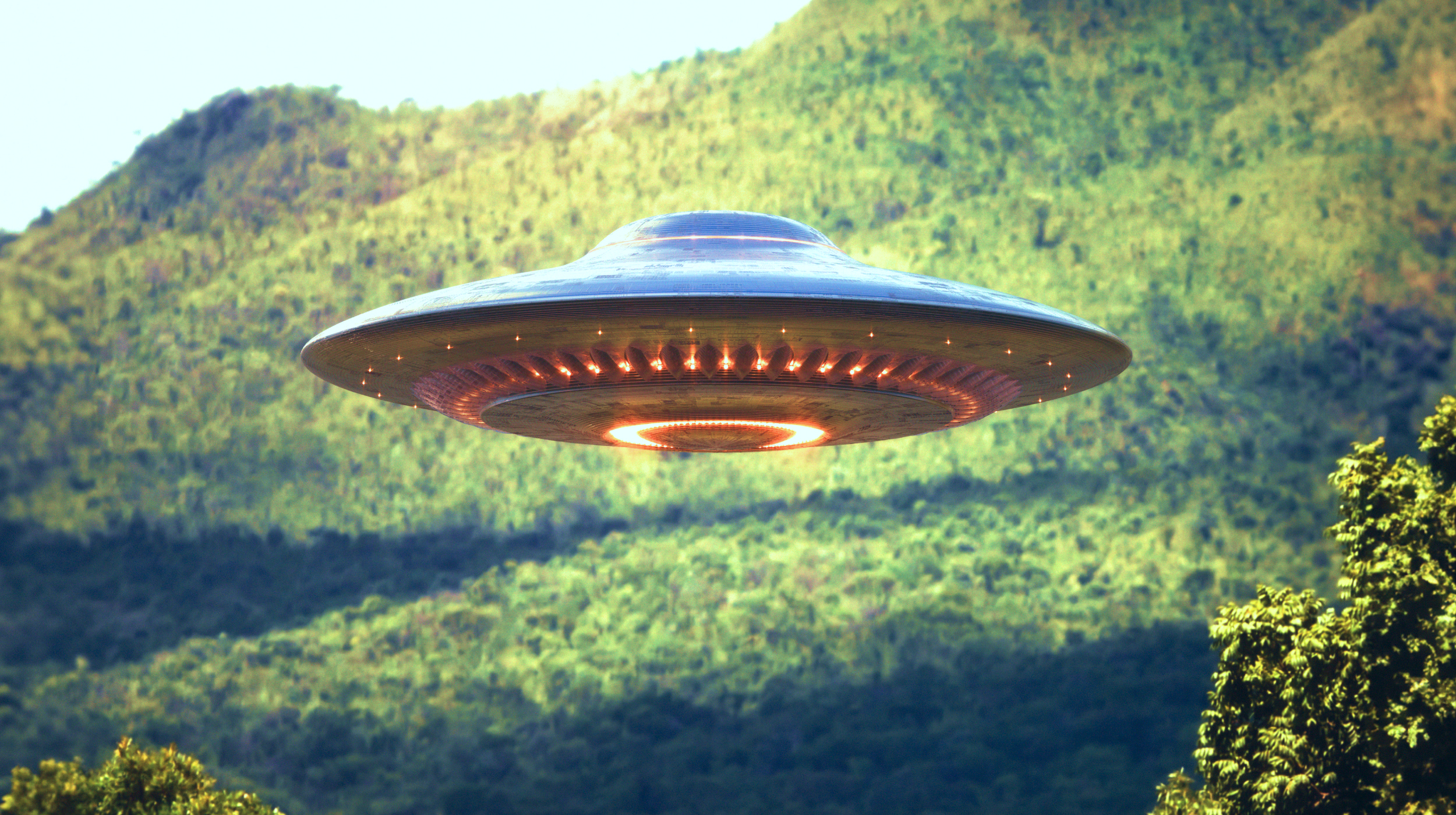 An ufo flying over a forest.