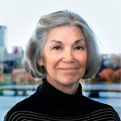 A woman with gray hair standing in front of a city.