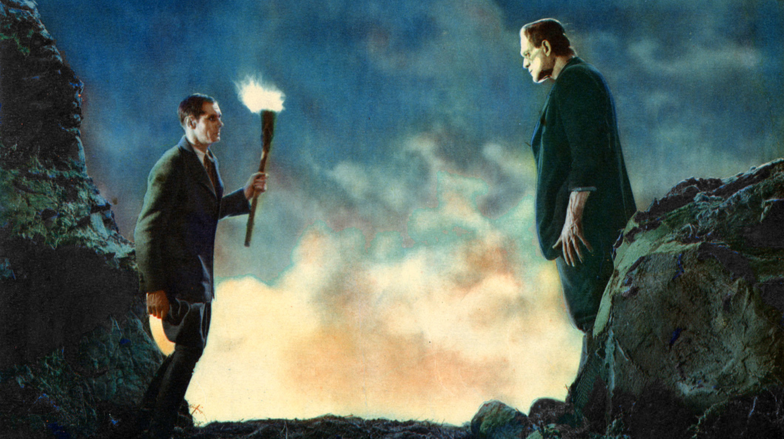 Two men standing on top of a mountain with a torch.