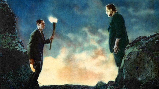 Two men standing on top of a mountain with a torch.