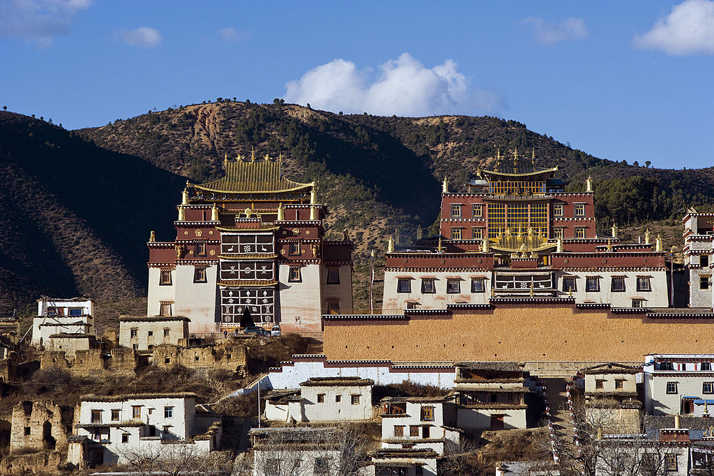 A large building on top of a hill with mountains in the background.