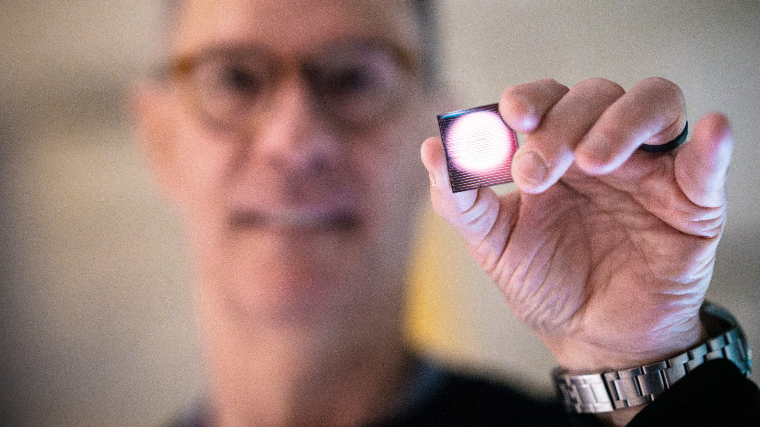 A man is holding up a small device for seizure detection.