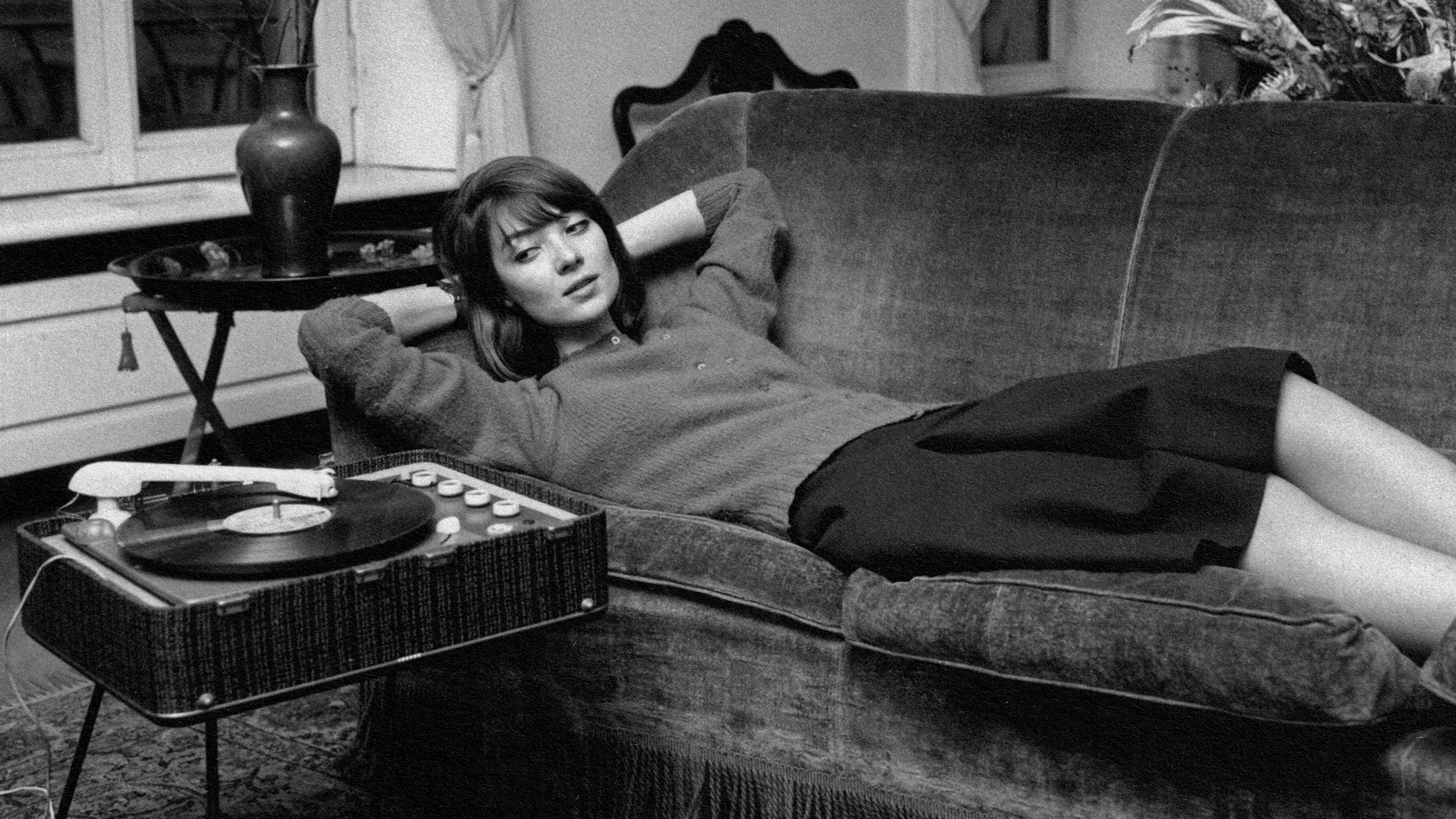 A woman with a music personality enjoying a record player on a couch.