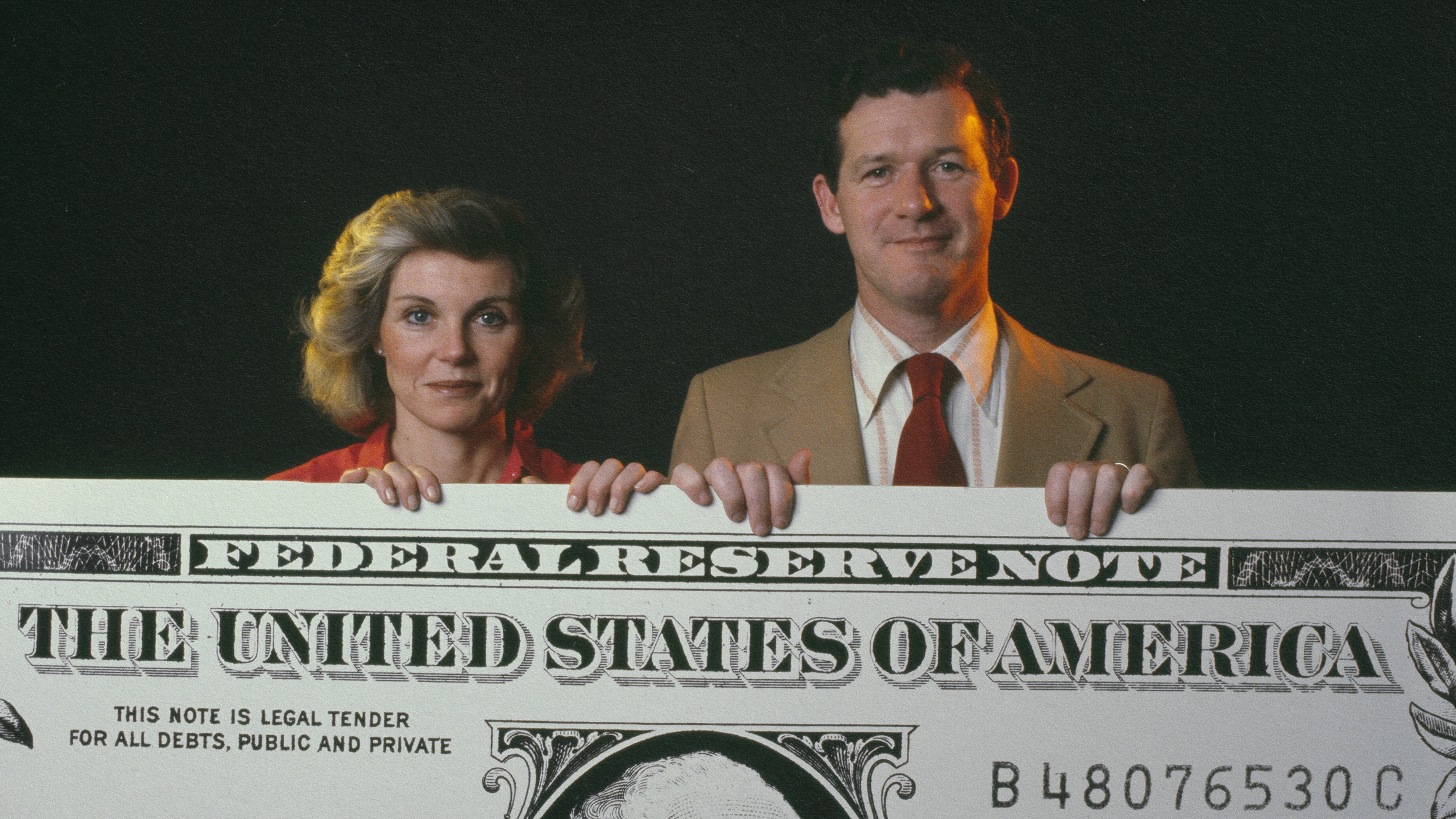A couple displaying a generous federal reserve note.