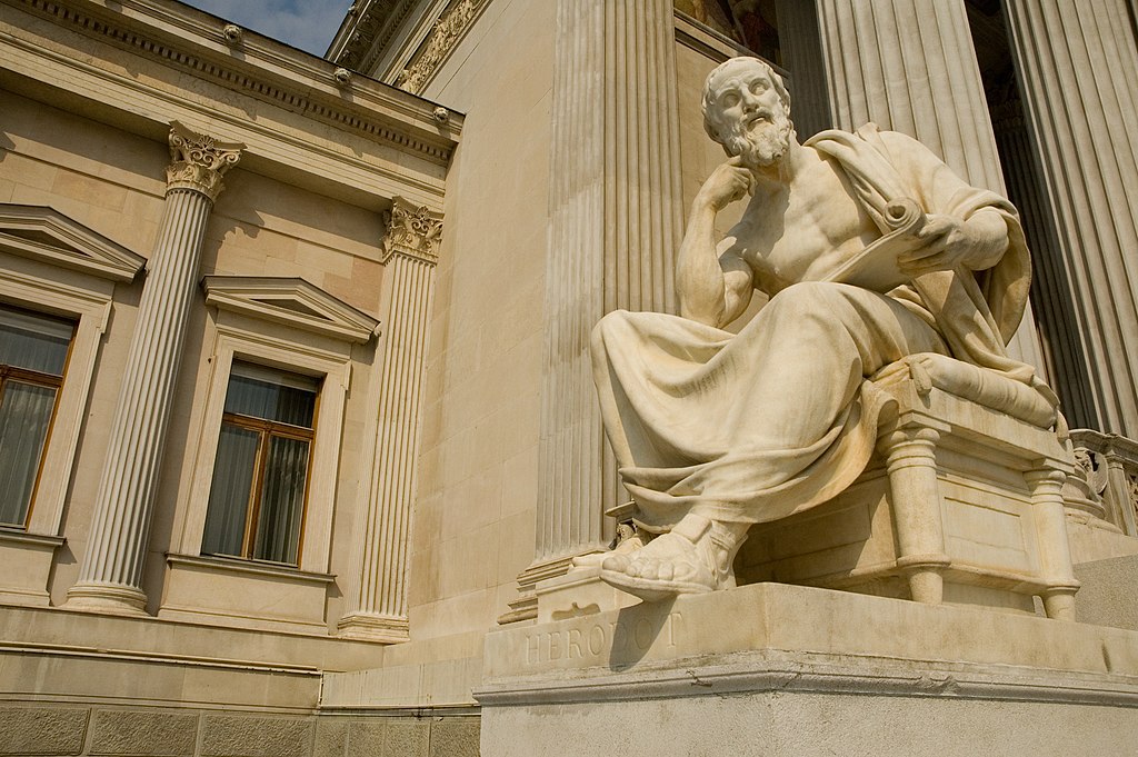 A statue of a man sitting in front of a building.