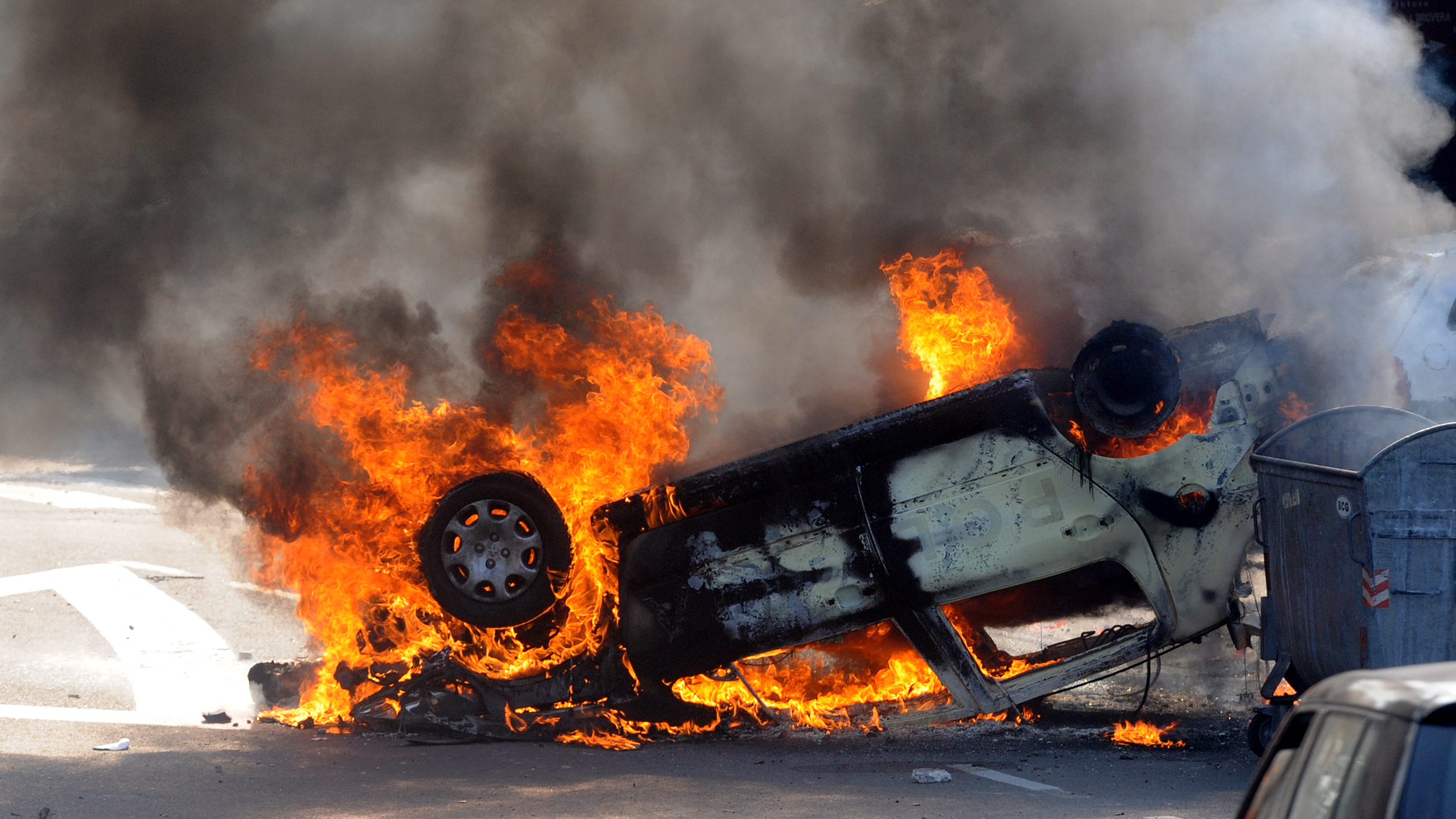 A burning car on the side of the road.