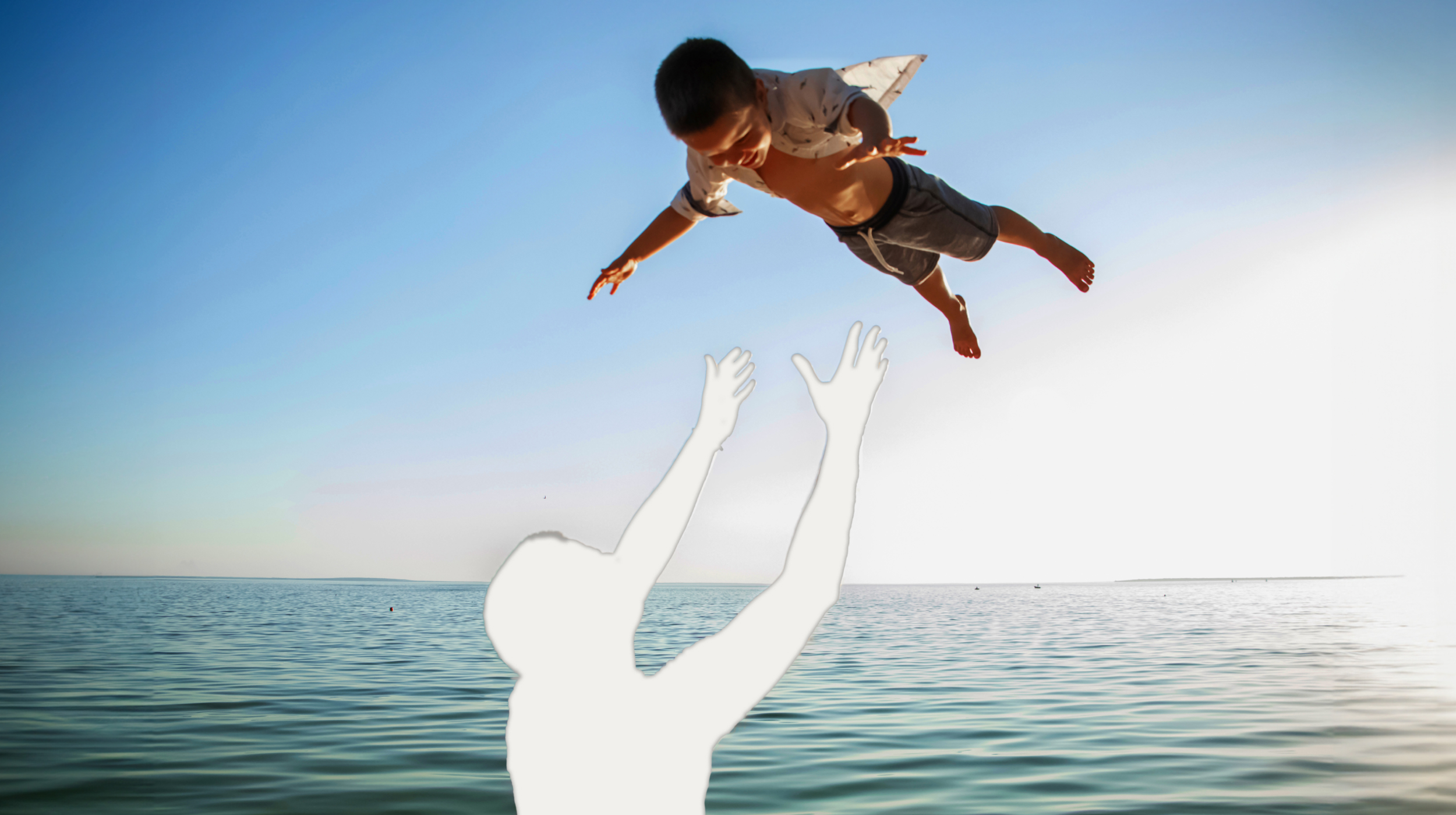 A silhouette of a boy jumping into the water.