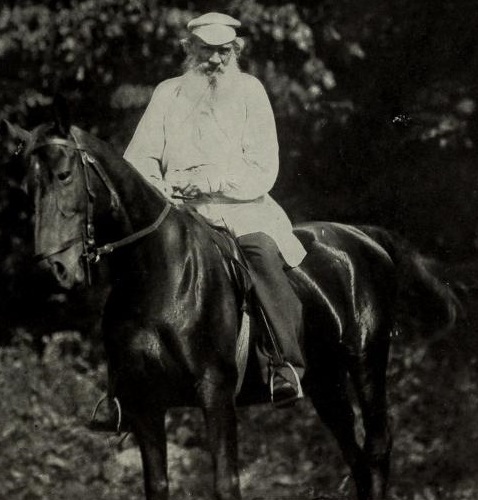 An old black and white photo of a man riding a horse.