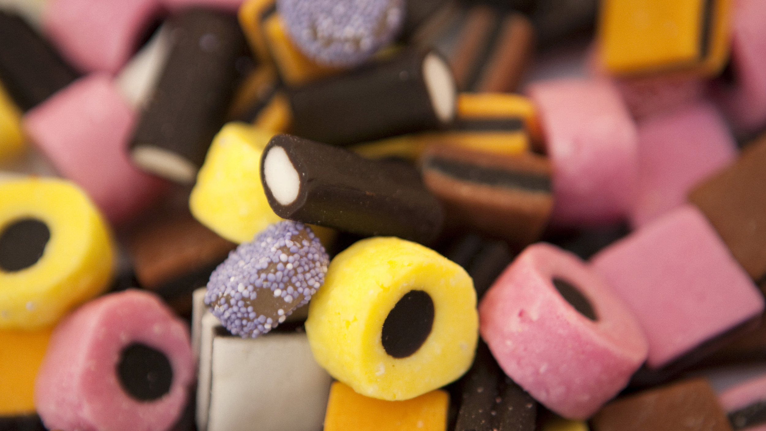 A close up of a pile of different colored candies, including one or two varieties infused with ammonium chloride.