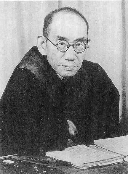 A black and white photo of a man sitting at a desk.