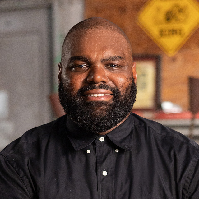 A black man with a beard in a black shirt.