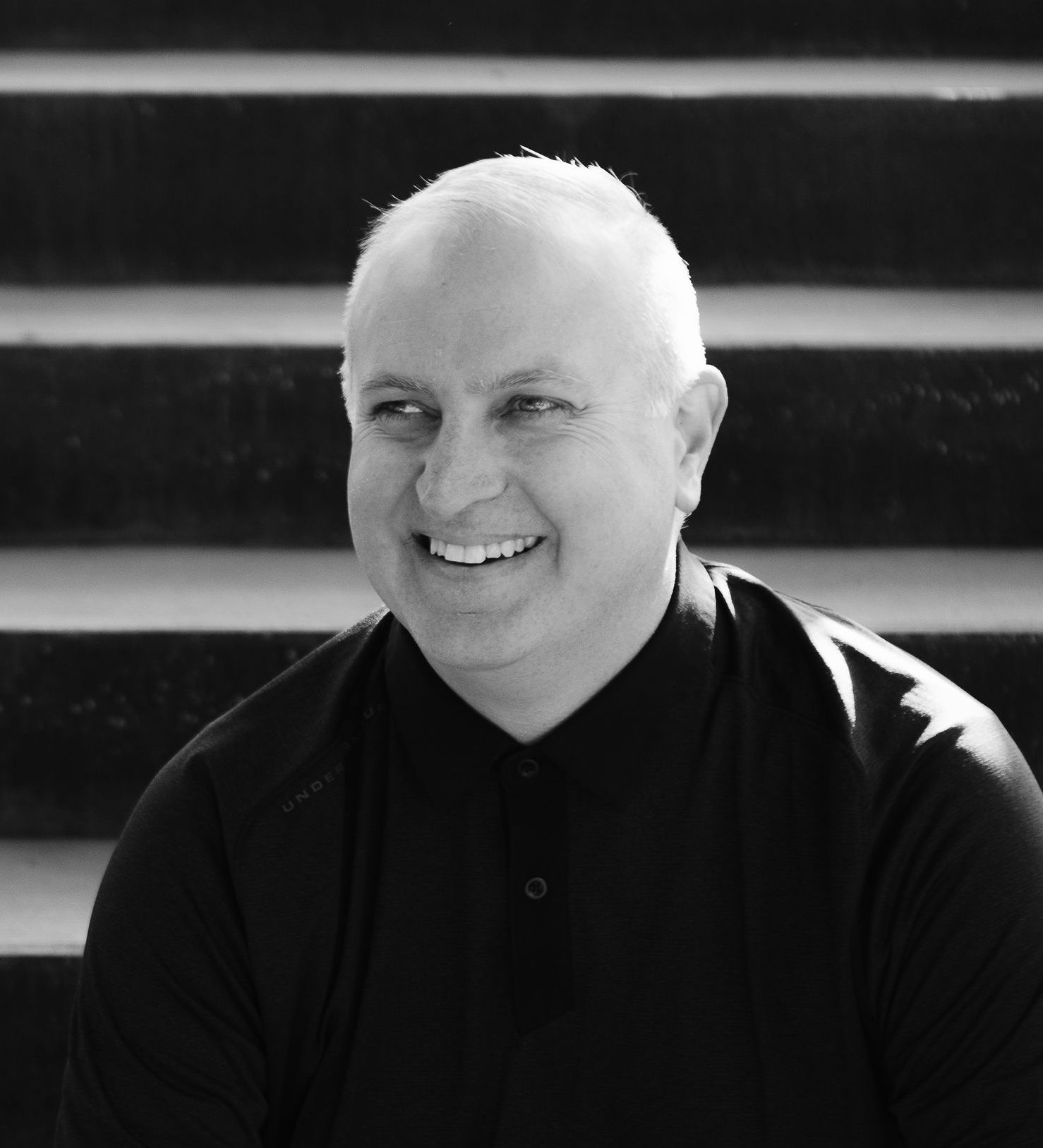 A black and white photo of a man smiling.