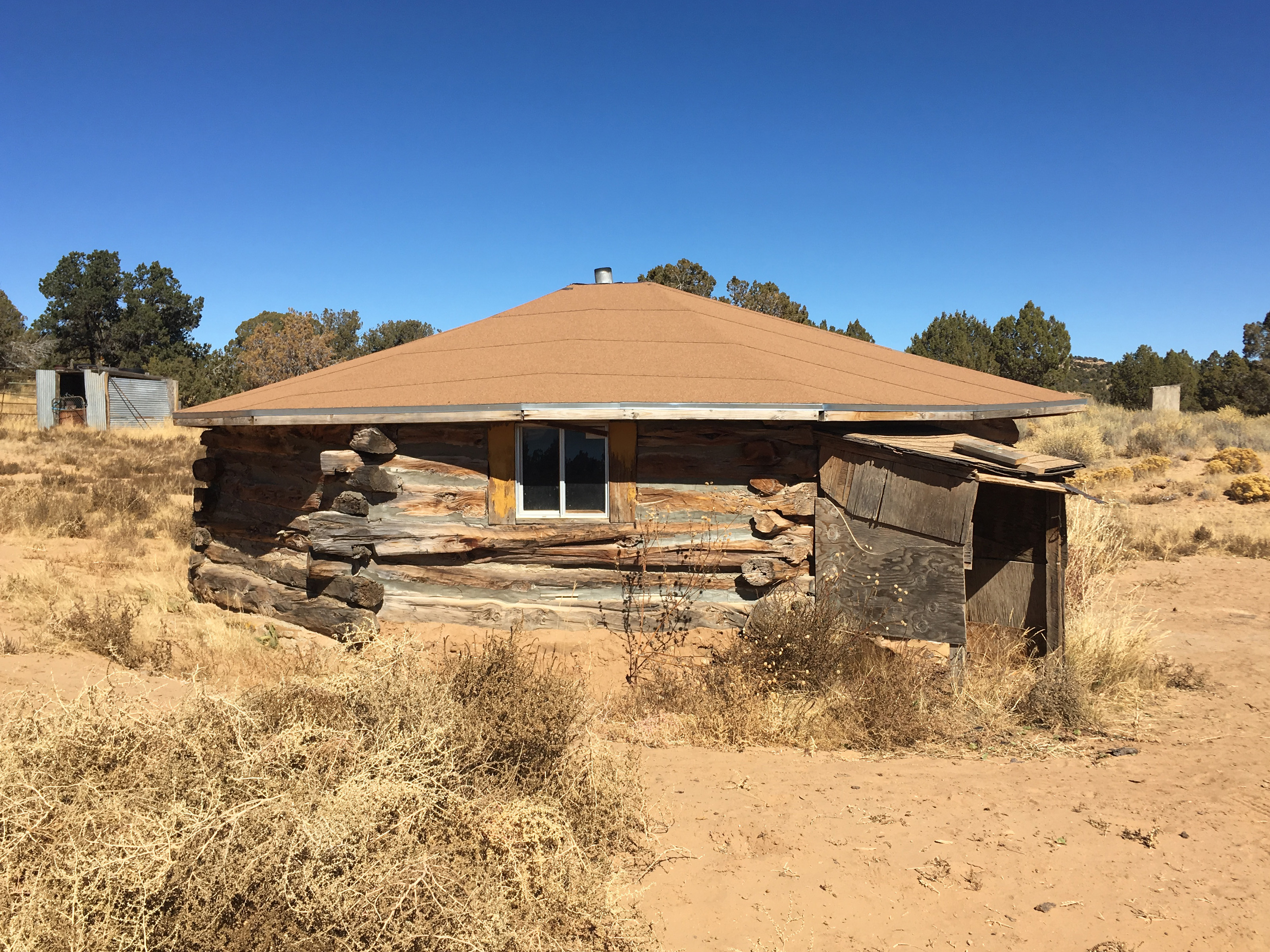A cozy log cabin nestled in the barren desert landscape, inspired by Navajo design.