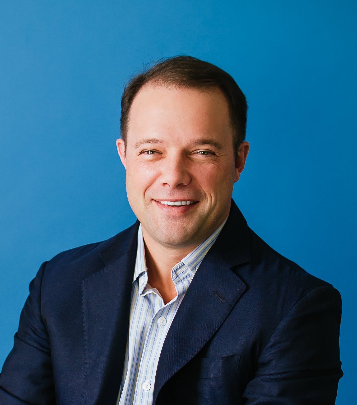 A man in a blue shirt is smiling.