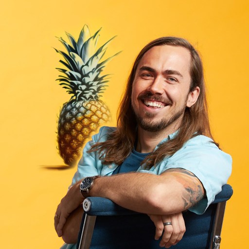A man sitting in a chair with a pineapple in front of him.