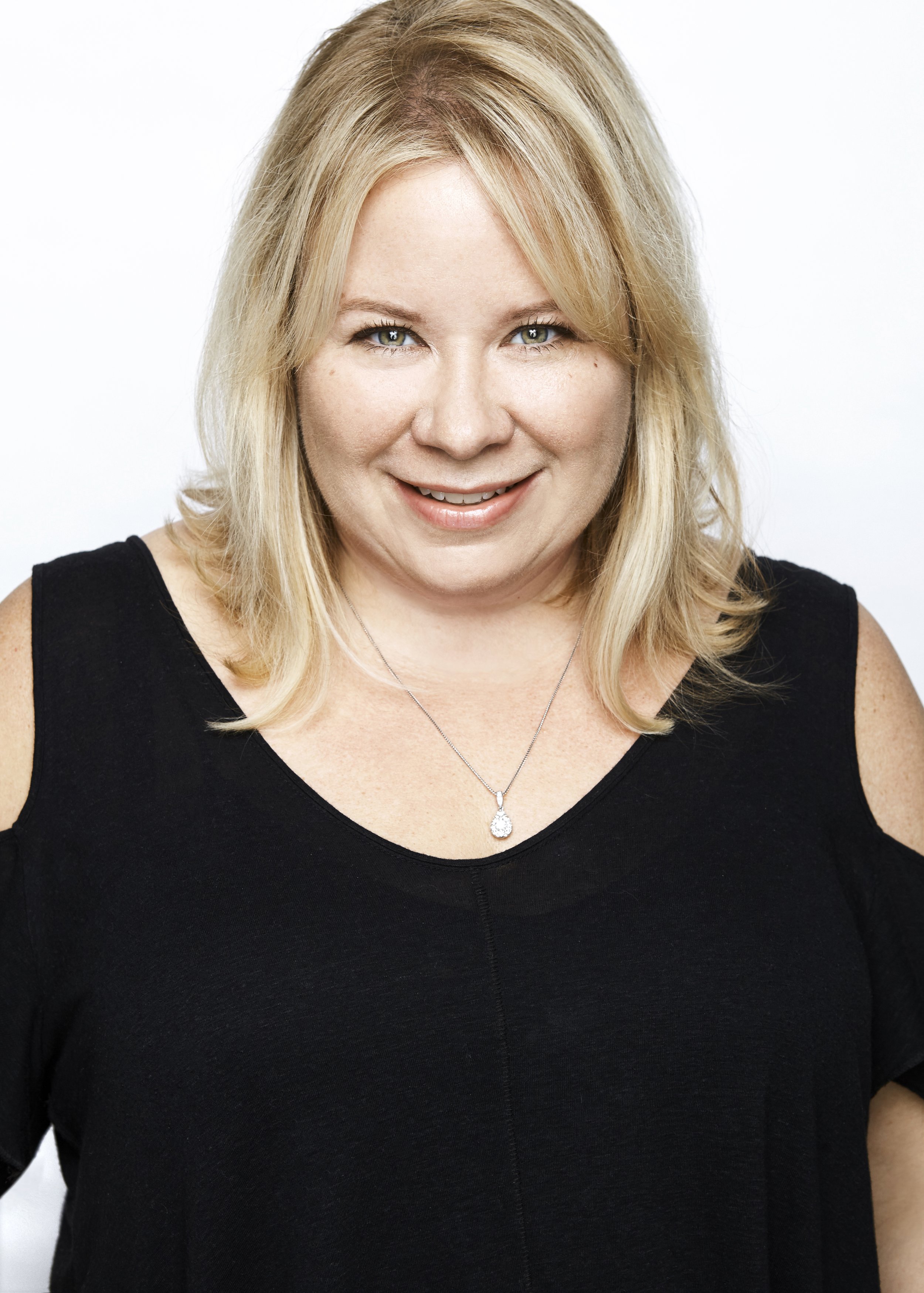 A blonde woman in a black top posing for a photo.