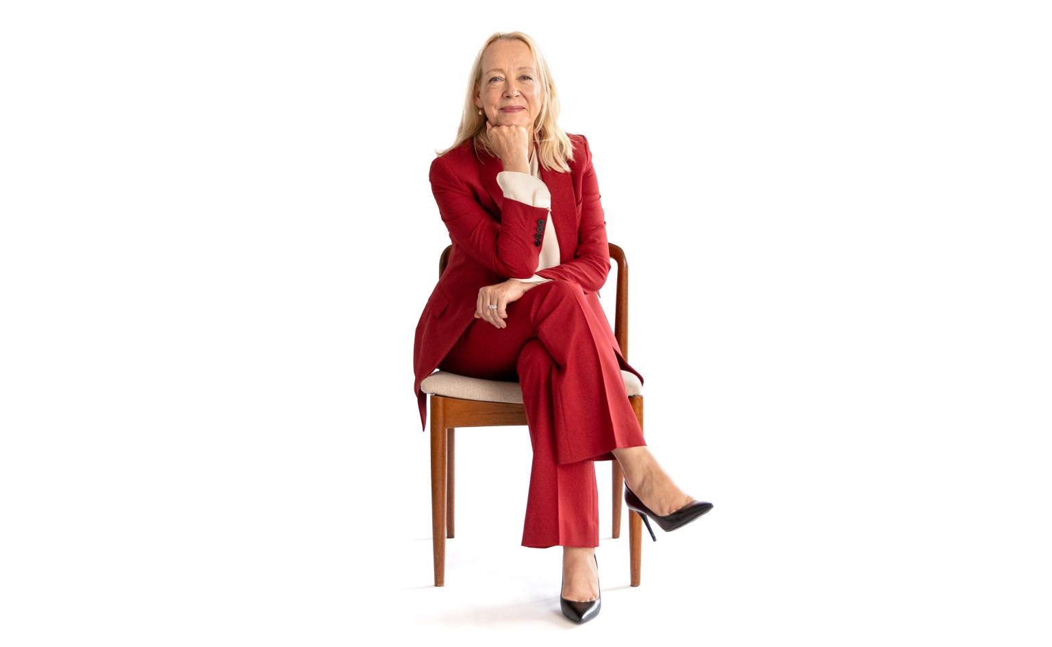 A woman in a red suit sitting on a chair.
