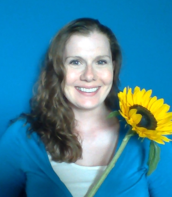 A woman holding a sunflower in front of a blue background.