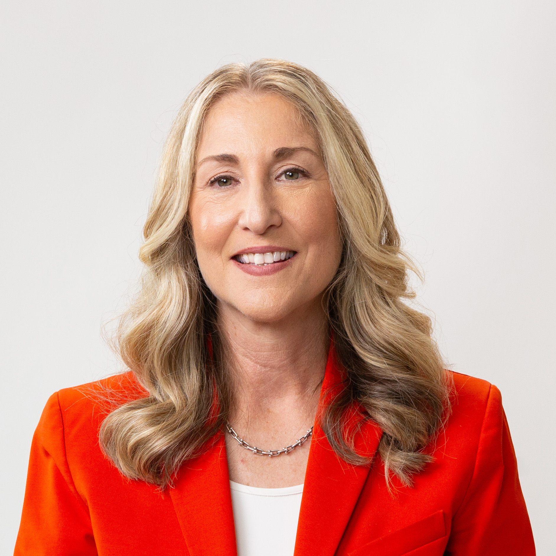 A woman wearing an orange blazer and white shirt.