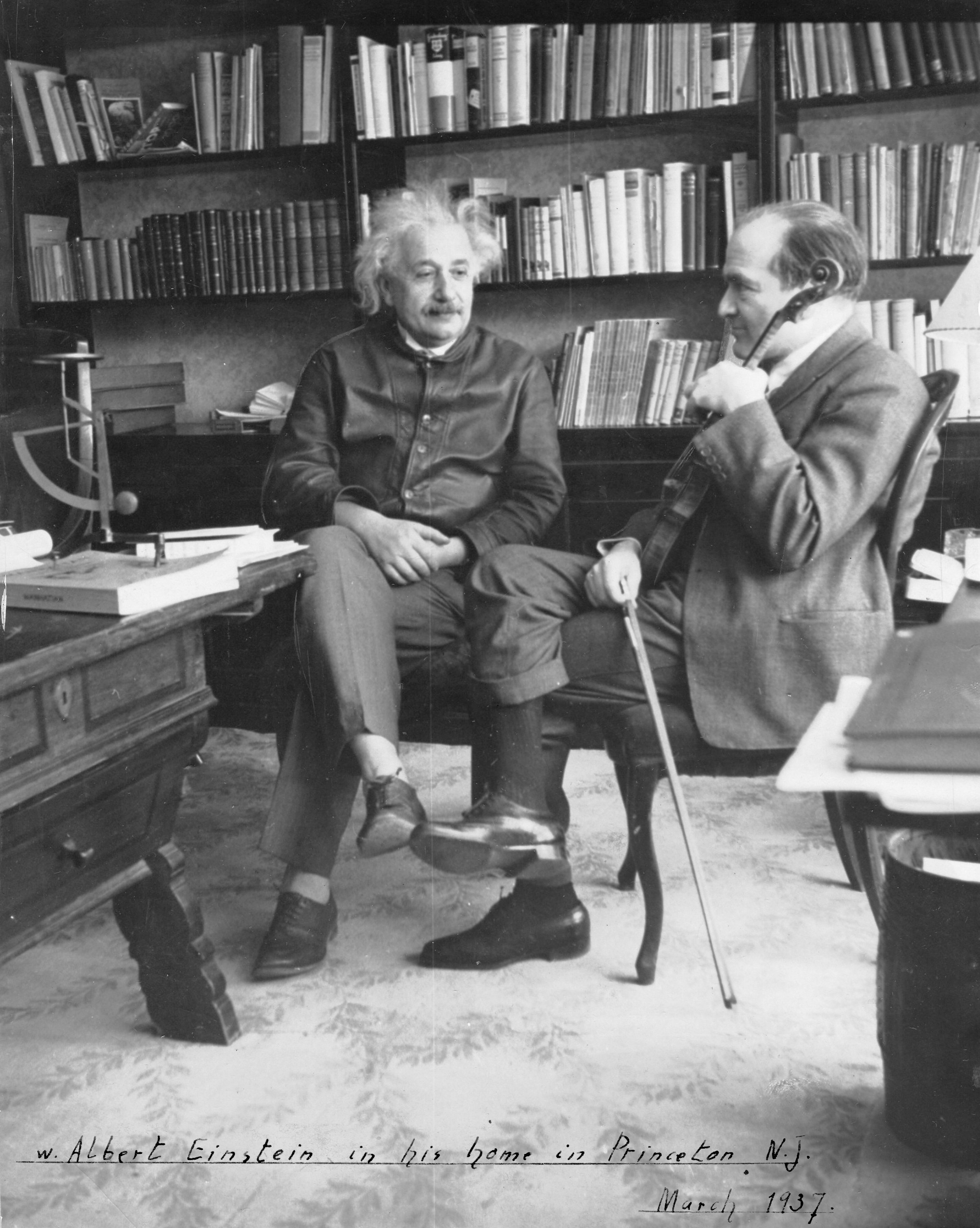 Two men sitting in a room with books.