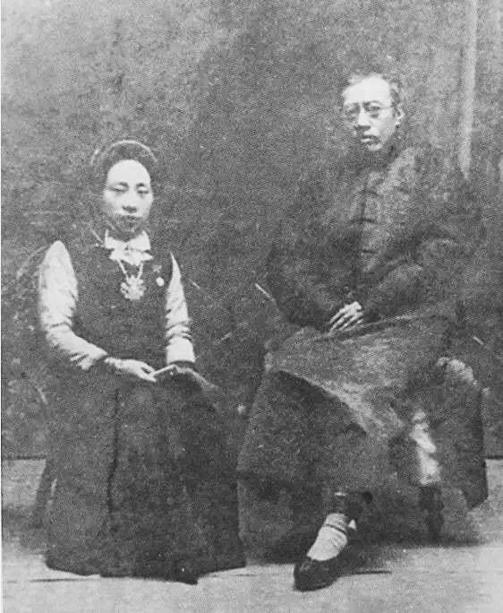 An old photo of a man and woman engaged in a cozy conversation on a chair.