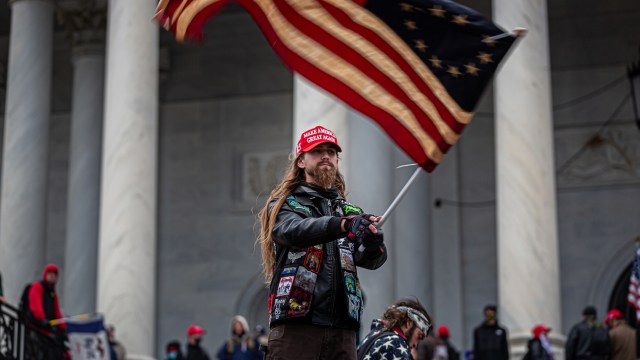 A man waving an american flag in front of a group of people.
