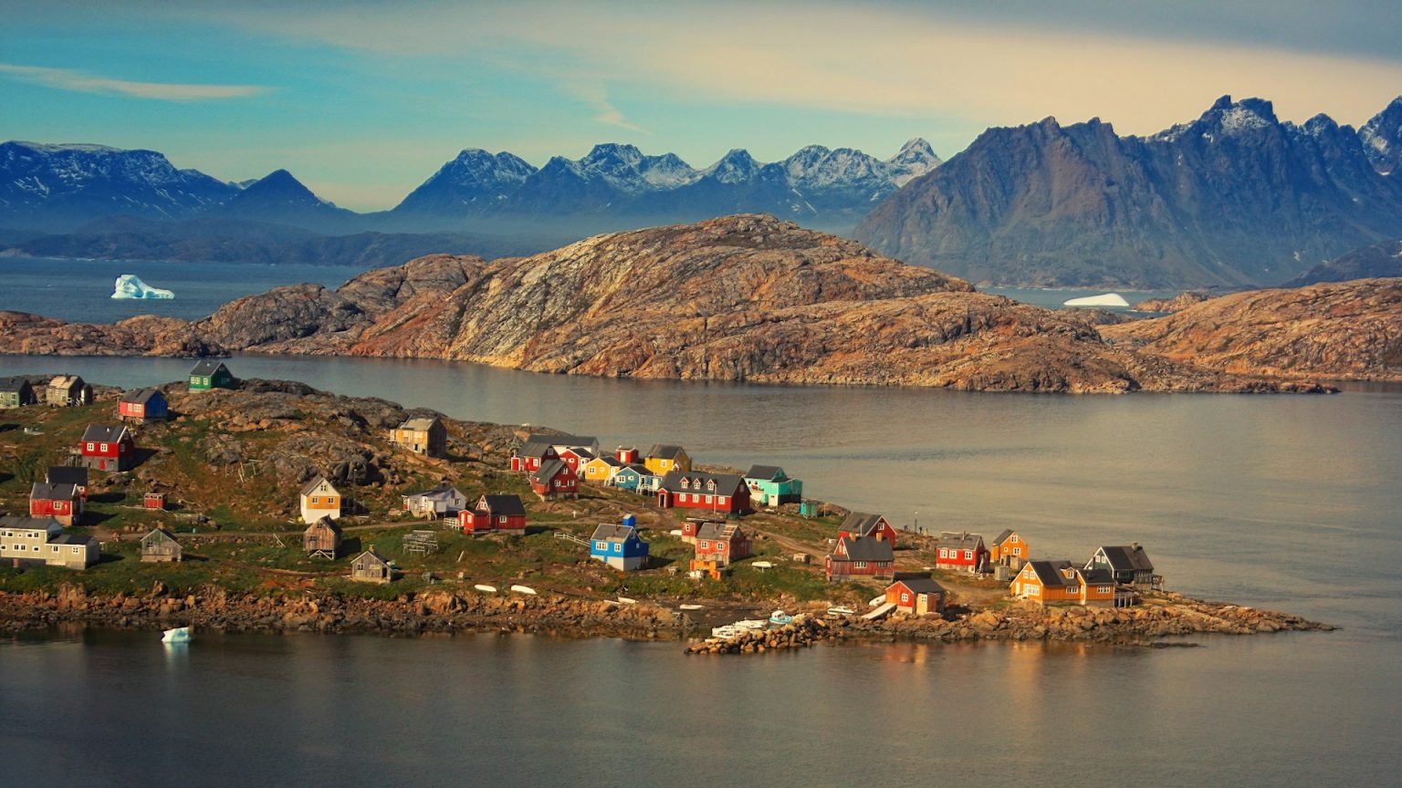 A colorful village sits on the shore of a body of water.
