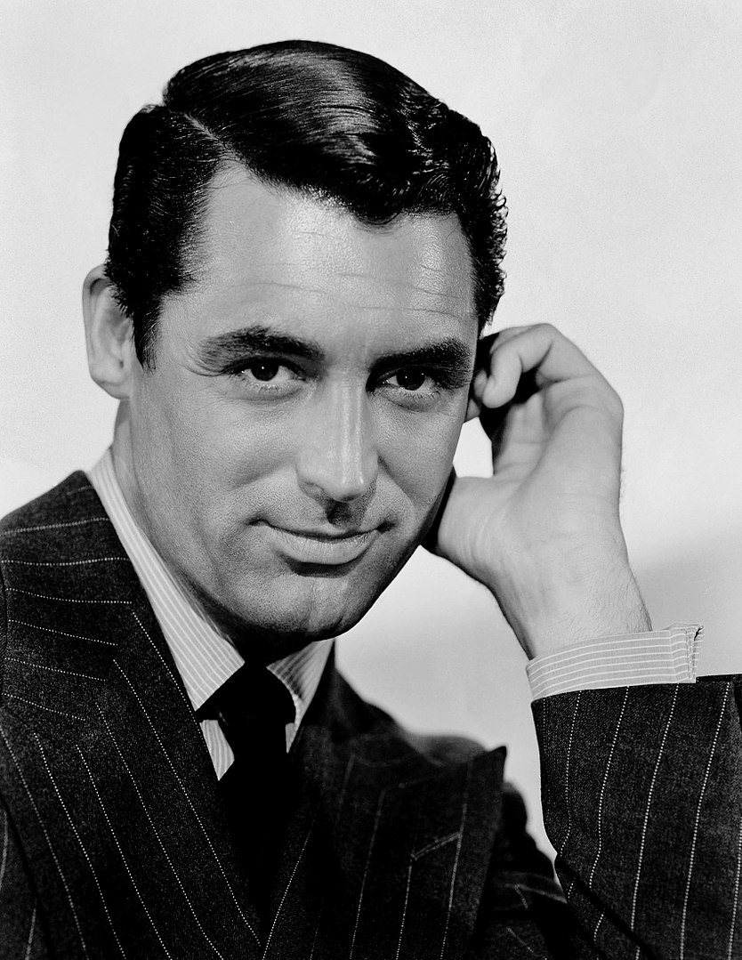 A man in a suit holding his hand to his ear.